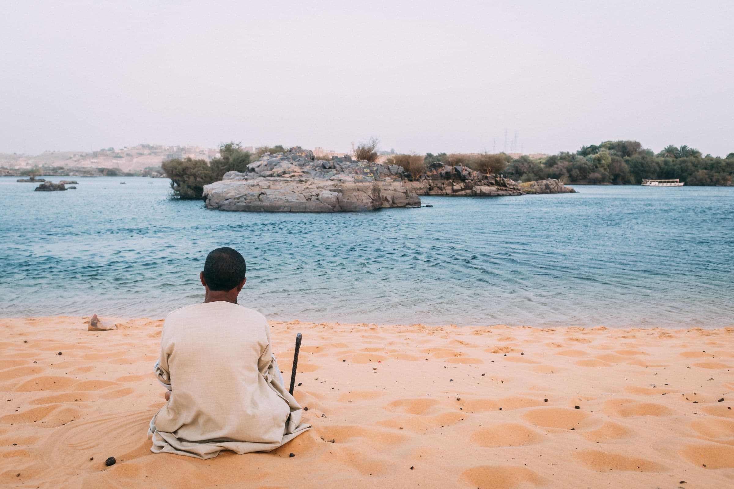 A man resting on the golden sand of the Nile shore near Aswan