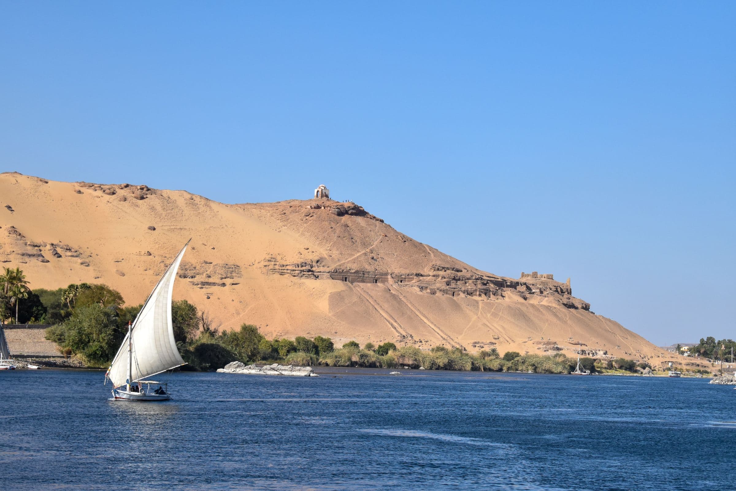 A felucca sailing below the desert hills of Aswan’s west bank