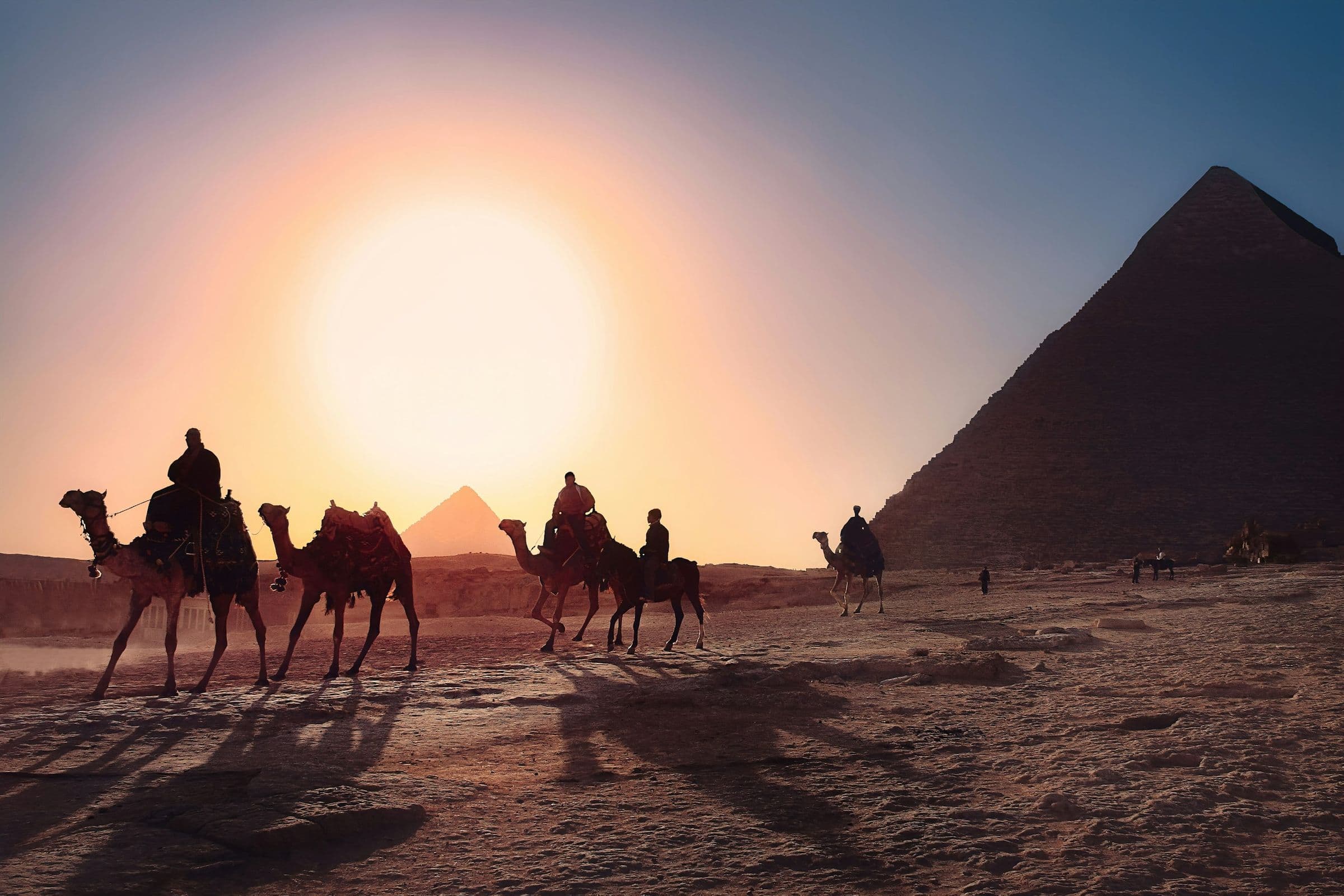 A camel caravan crossing the Giza plateau at sunset