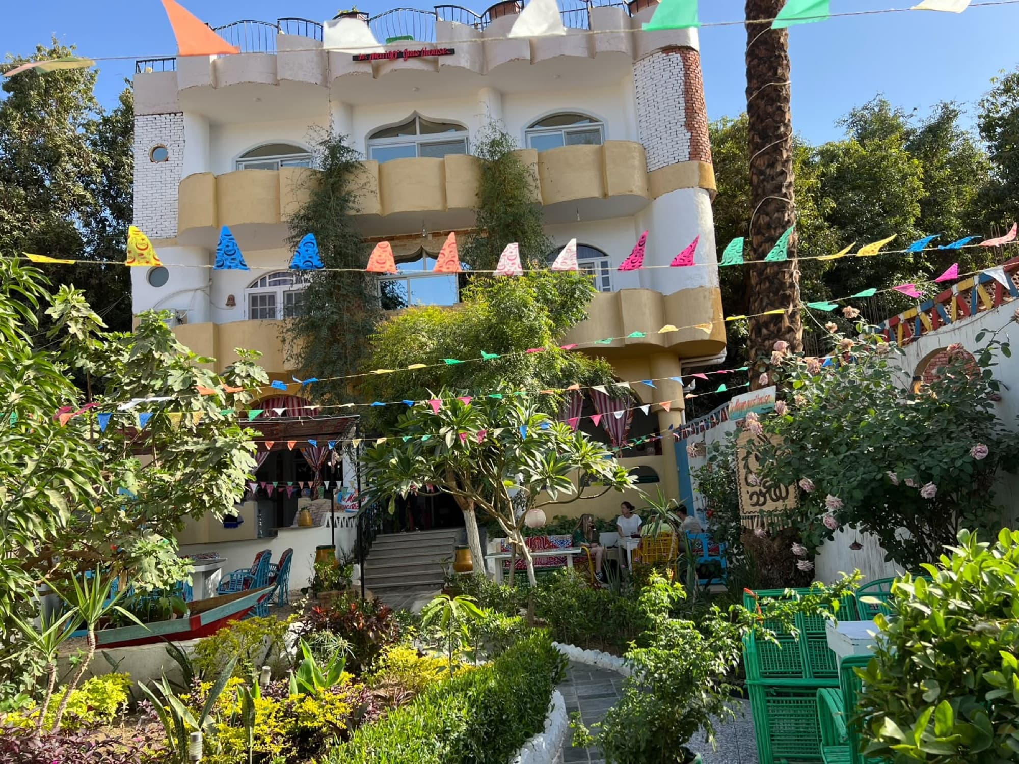 The yellow-and-white façade of Mango Guesthouse above its garden, strung with colourful bunting