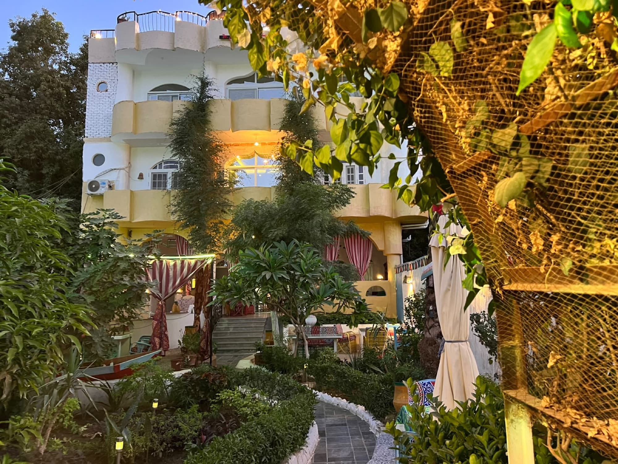The garden in the warm evening light, with the guesthouse rising behind