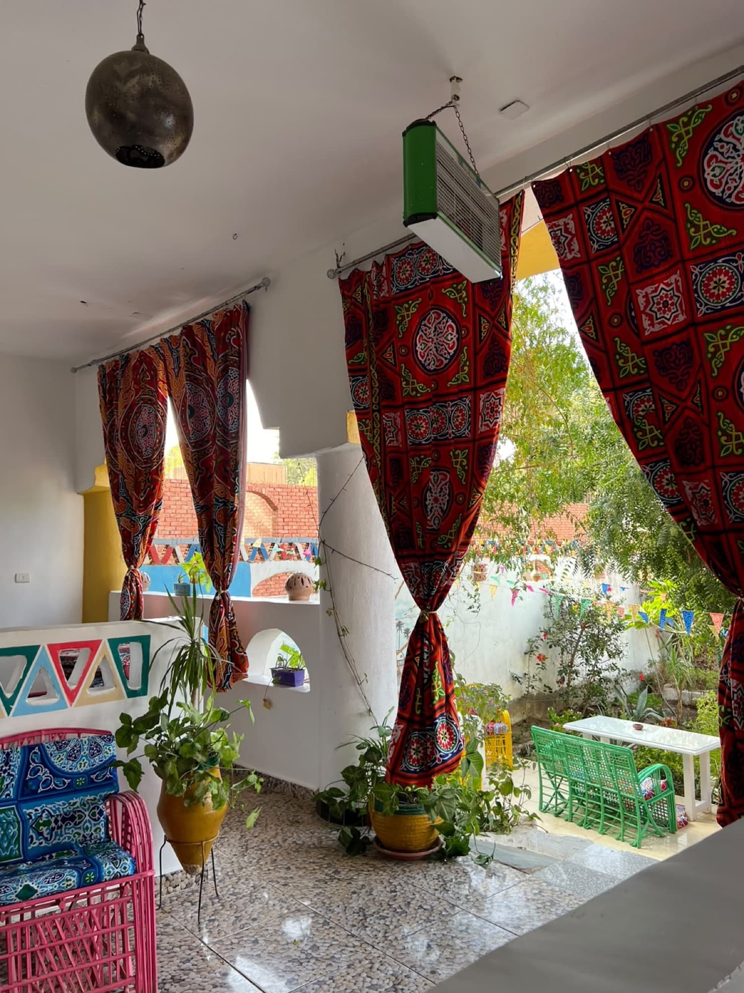A bright hall with red tentmaker curtains opening onto the garden