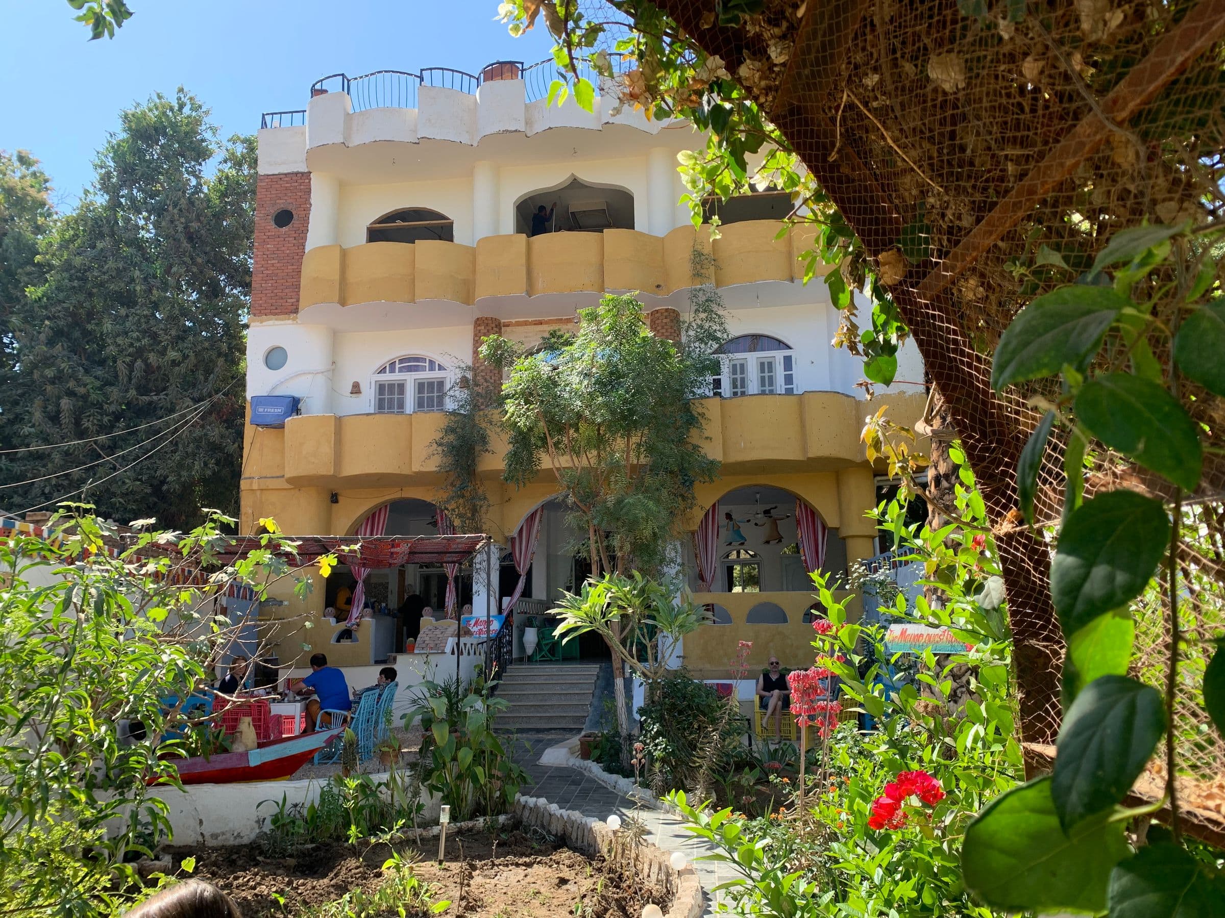 The yellow-and-white Mango Guesthouse among the gardens of Elephantine Island