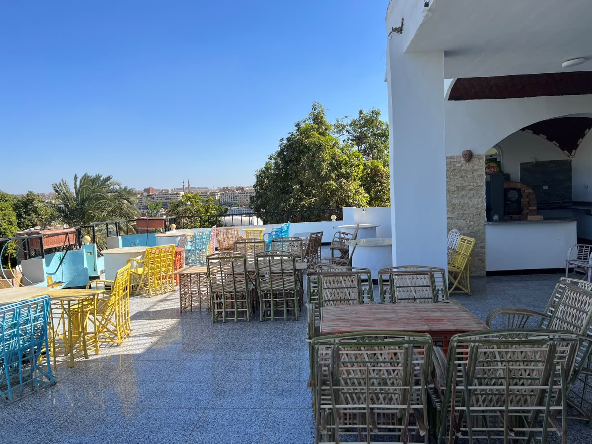 The rooftop terrace laid with cane chairs and tables under a clear Aswan sky
