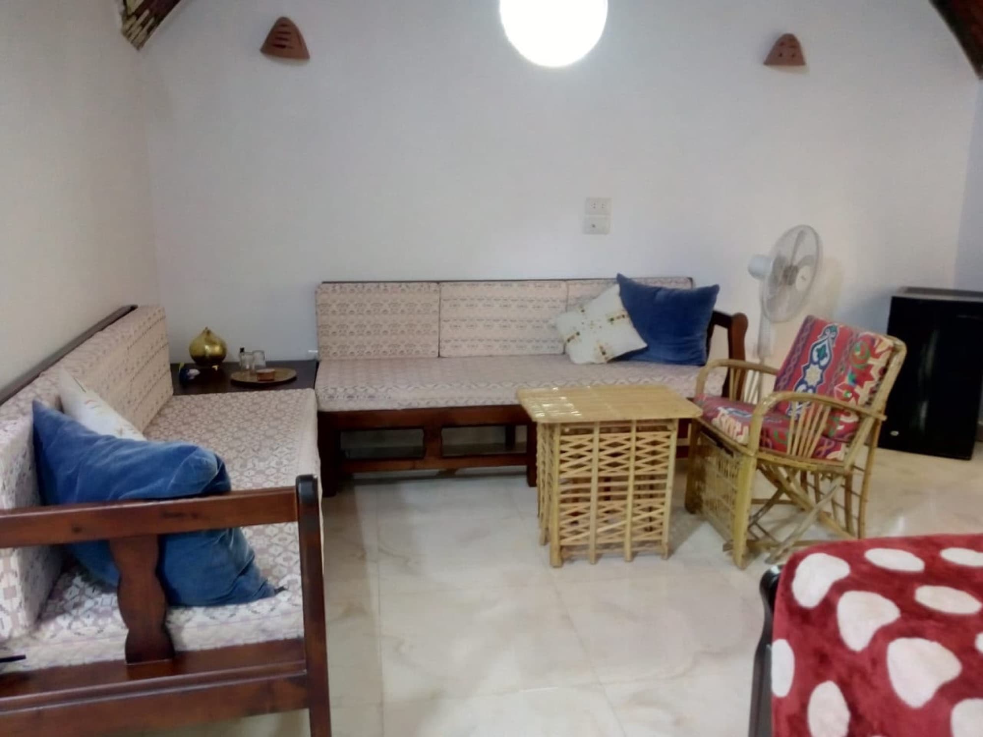 The sitting area of a guest room, with a wooden sofa and blue cushions
